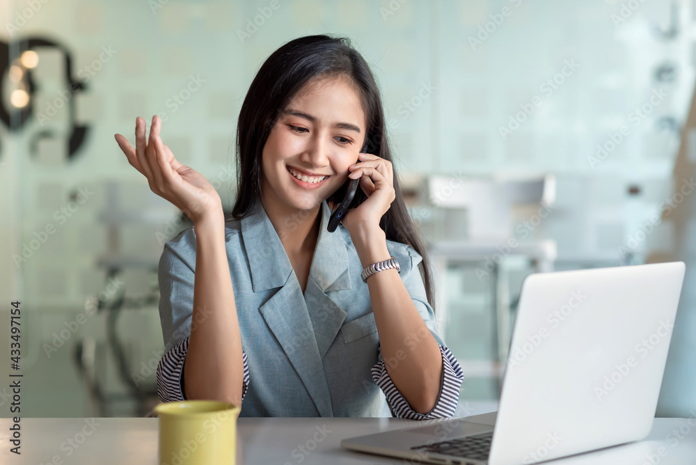 Asian businesswoman talking on the phone using laptop at the office. Asian businesswoman talking on the phone using laptop at the office.