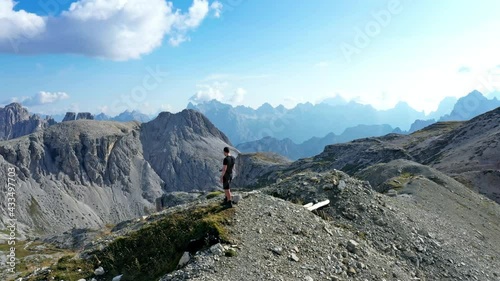 Young man on top of Bullelejoch mountain peak. Aerial drone shot surrounding him
