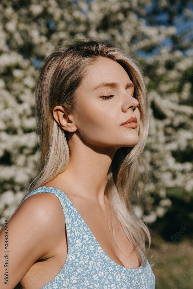 Young woman with long blonde hair outdoors, in a park, on cherry tree in bloom background. Young woman with long blonde hair outdoors, in a park, on cherry tree in bloom background.