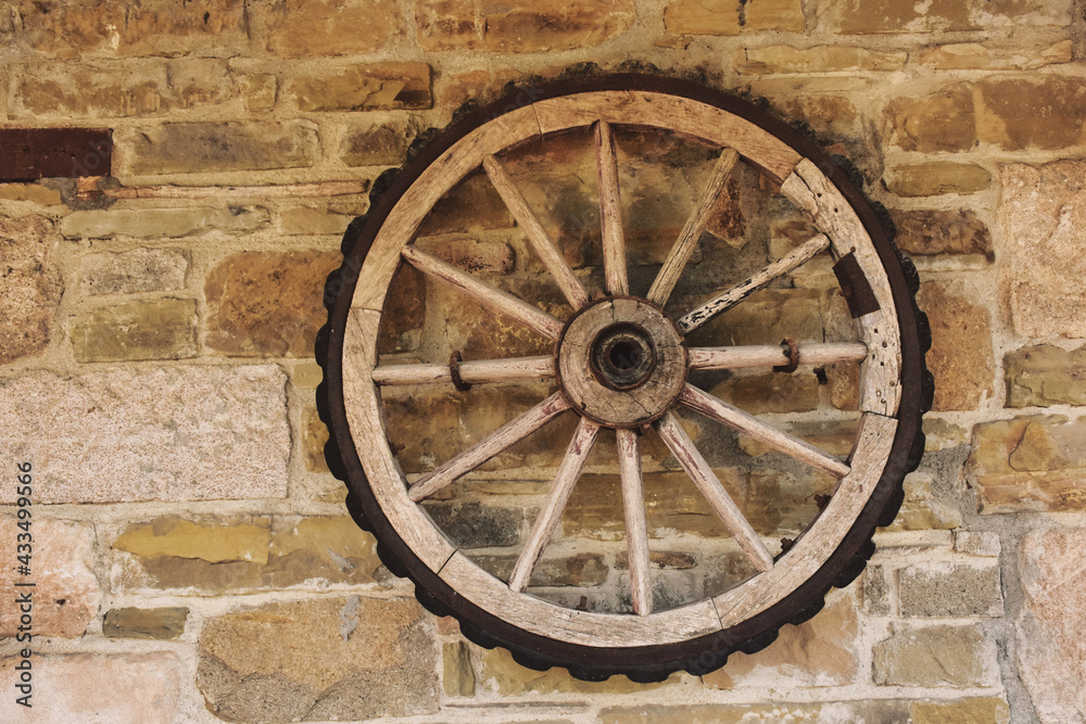 A vintage cart wheel on an old stone wall