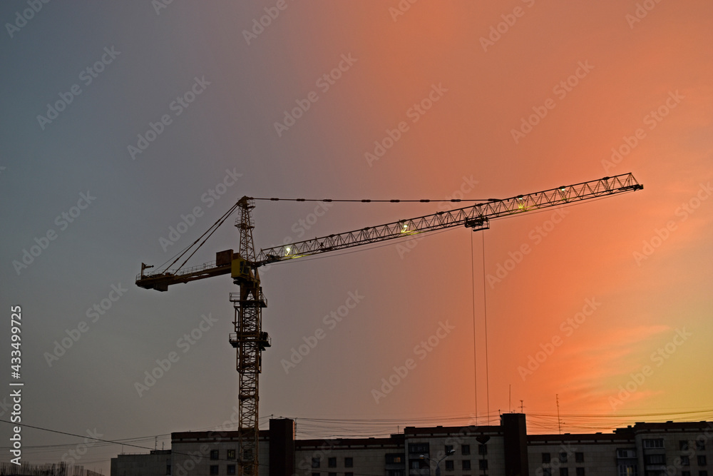 Tower crane in the city on the background of a beautiful sunset sky Tower crane in the city on the background of a beautiful sunset sky