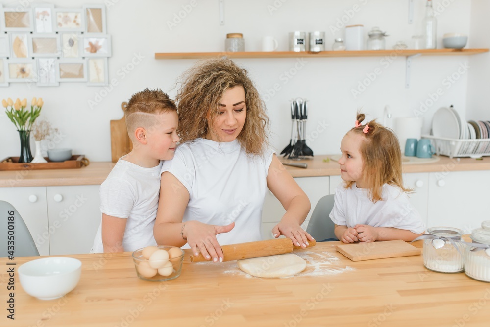 An attractive smiling family of mother, and two children, boy, girl, son, daughter cookies in a kitchen at home