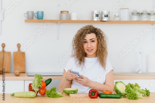 Young woman preparing vegetable salad in her kitchen. Healthy lifestyle concept beautiful woman with mixed vegetable. © Serhii