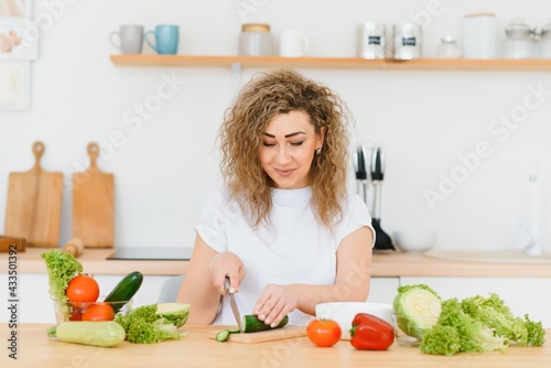 Woman making salad in kitchen. Healthy eating lifestyle concept with beautiful young woman cooking in her kitchen.