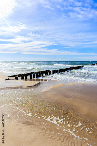 Wooden breakwaters and sea waves on beach in Dzwirzyno village near Kolobrzeg town, Baltic Sea coast, Poland
