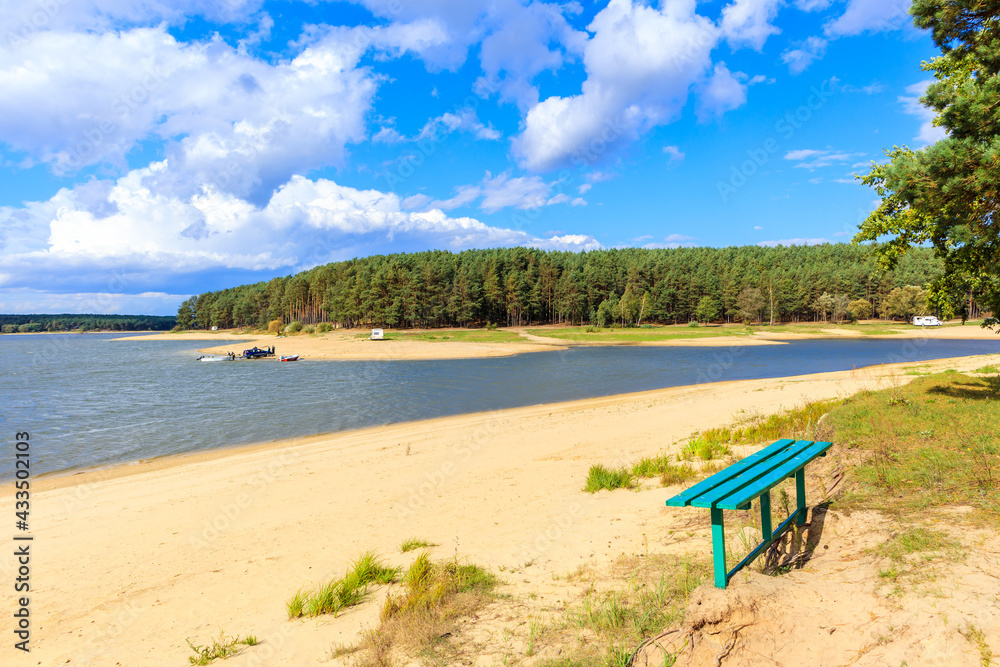 Wooden bench on beautiful sandy beach at Chancza lake in Swietokrzyskie region in central Poland
