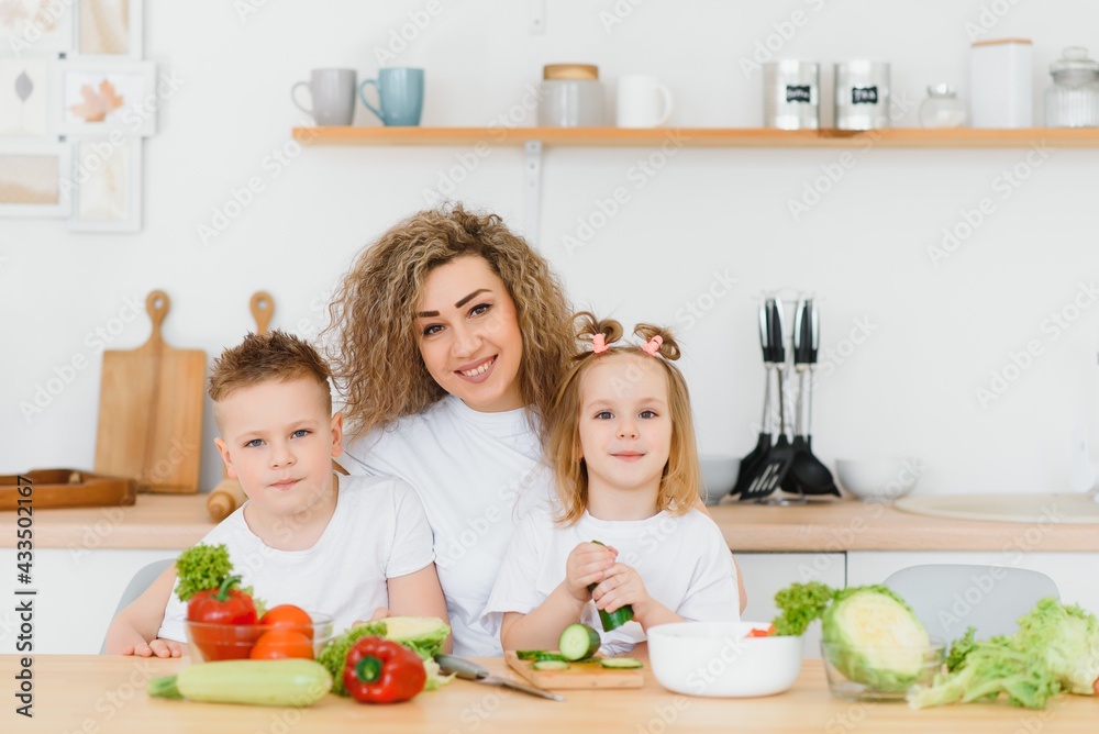 Family in a kitchen. Beautiful mother with children. Lady in white blouse. Family in a kitchen. Beautiful mother with children. Lady in white blouse.
