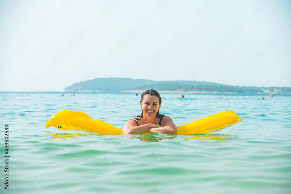 portrait of pretty smiling woman on yellow inflatable mattress