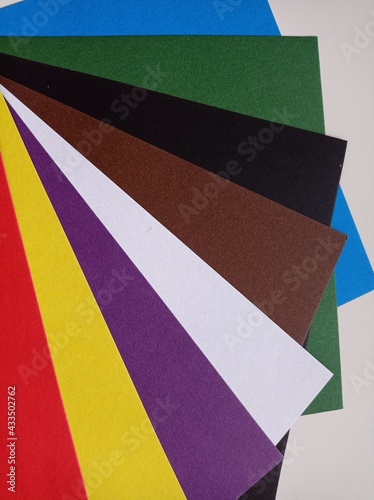 Colored paper spread out in a fan.Background. Red, Yellow, Purple, White, Blue, Brown, Green, Brown