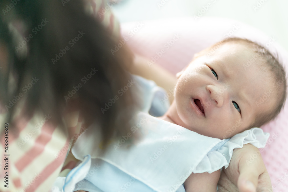 Closeup on the face of the baby in the arms of the mother, she was looking at the mother and acting innocent. (Soft focus) Closeup on the face of the baby in the arms of the mother, she was looking at the mother and acting innocent. (Soft focus)