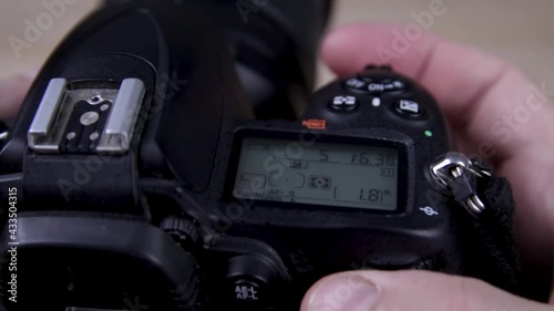 Male photographer adjusts settings on DSLR camera close up photo