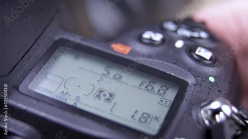 Photographer holding DSLR camera adjusting settings - close up