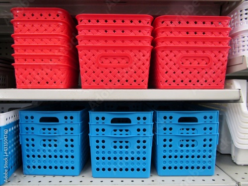 Red and blue plastic mesh organizer storage baskets on shelves