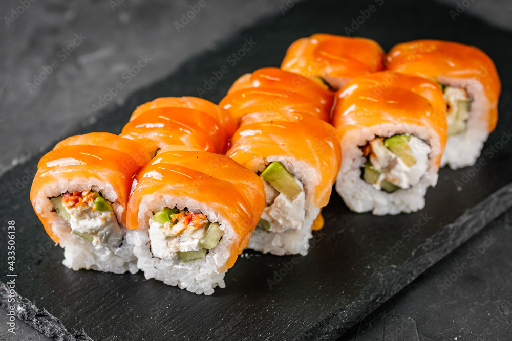 appetizing sushi roll philadelphia with avocado cheese eel cucumber and salmon on a black stone plate appetizing sushi roll philadelphia with avocado cheese eel cucumber and salmon on a black stone plate
