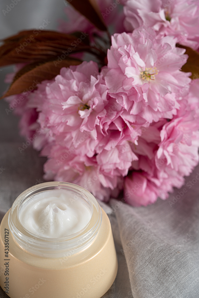 Anti wrinkle face cosmetic cream or mask  with herbal flowers. Skin and body care.Beautiful pink flowers background.