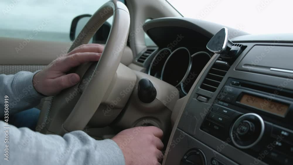 Man's hand puts the car key in the keyhole, starting the car. Man's hand puts the car key in the keyhole, starting the car.