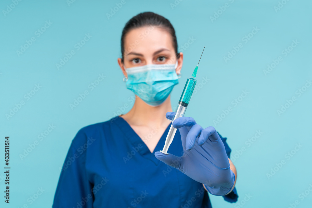 Studio shot of confident young woman doctor wearing medical mask and rubber gloves holding Covid-19 vaccine in her hand