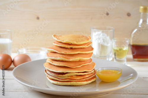 pancakes with honey and ingredients for cooking on the table