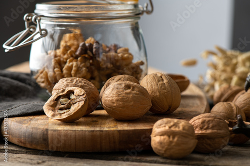 Tasty walnuts with cracked split nutshells, jaw and dragon nutcracker on rustic napkin and wood table photo