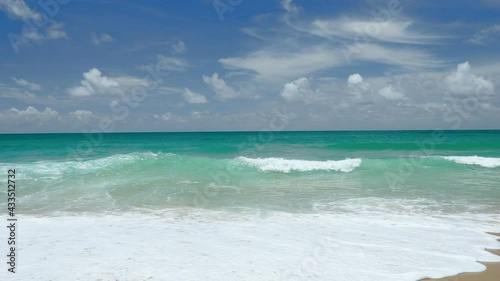 Beautiful beach on a sunny day, the horizon and clouds visible. Sea with turquoise water some waves gushed towards the shore and bubbles covered sand Tropical beach on the high season in Thailand.