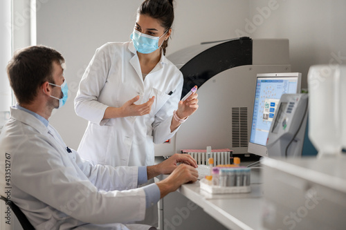 Doctor and female technician with face mask working together in the laboratory. 