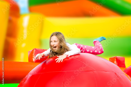 Fototapeta Happy little girl having lots of fun on a inflate castle while jumping