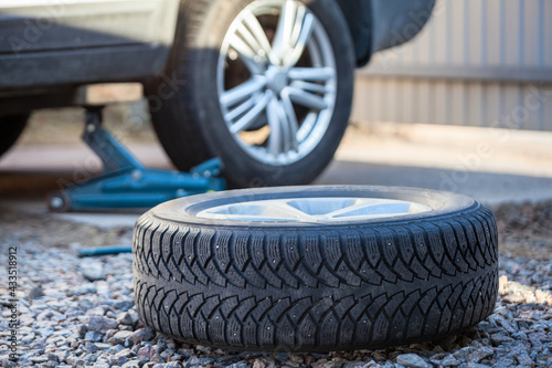 Seasonal winter tyre change. Snow tire lying on ground, is ready to install, spring photo