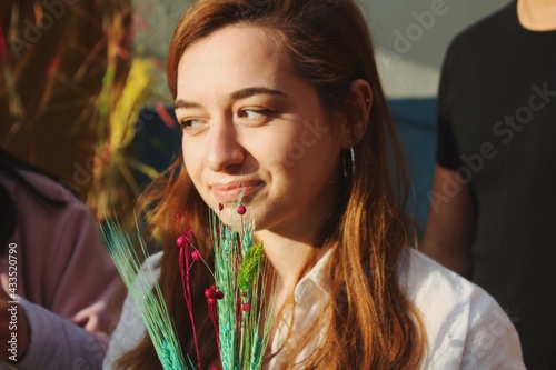 portrait of albanian young woman holding colorful flowers in group of friends outdoors  photo