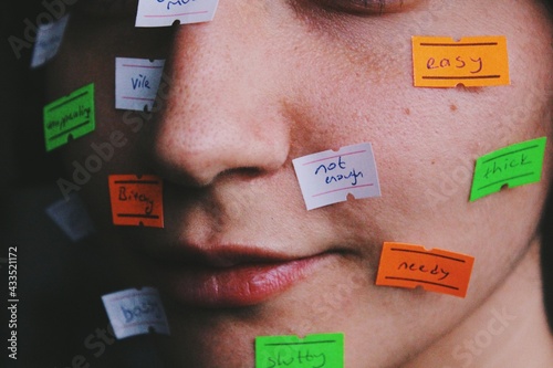 close up portait of young womans face with price tag labels with words as gender roles, social norms, stereotypes, taboos society puts on women 