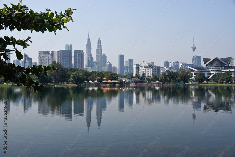 Naklejka premium Petronas Twin Towers, KL Tower, and Istana Budaya (opera house) viewed across the waters of Titiwangsa Lake, Kuala Lumpur, Malaysia
