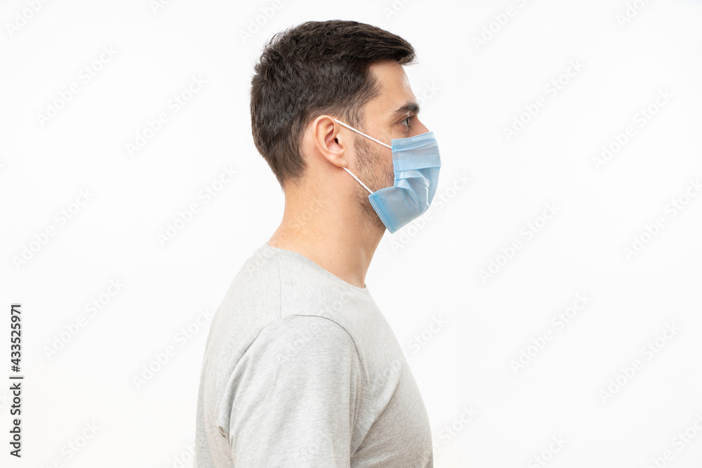 Right side view portrait of young man wearing t-shirt and face mask, isolated on gray background Right side view portrait of young man wearing t-shirt and face mask, isolated on gray background