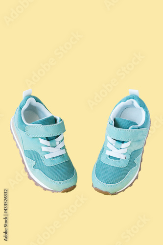 Green sneakers on yellow pastel background. Minimal concept for sport and activity.
