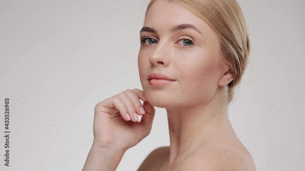 Beauty face. Caucasian young woman touching healthy skin portrait. Beautiful smiling girl with fresh glowing hydrated facial skin and natural makeup on light background at studio. Skin care concept. Beauty face. Caucasian young woman touching healthy skin portrait. Beautiful smiling girl with fresh glowing hydrated facial skin and natural makeup on light background at studio. Skin care concept.
