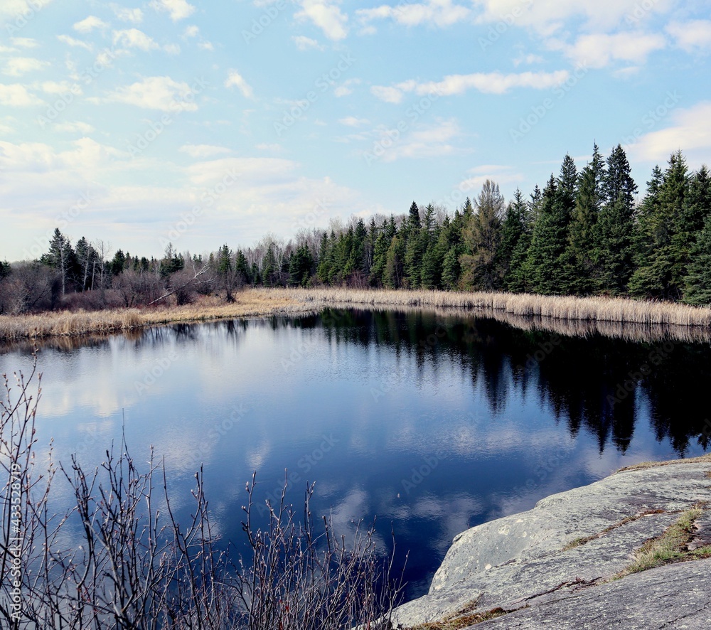 A small lake with rocky shores and surrounded by forest A small lake with rocky shores and surrounded by forest