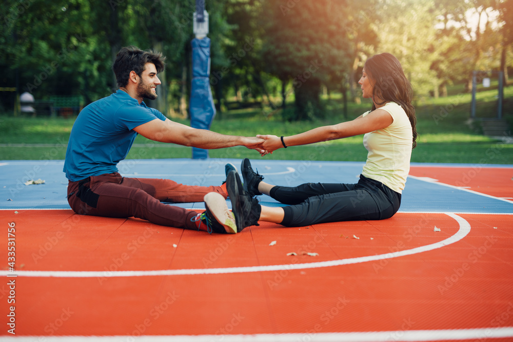 Obraz premium Beautiful young couple enjoying together on basketball court. Bright sunny summer day..