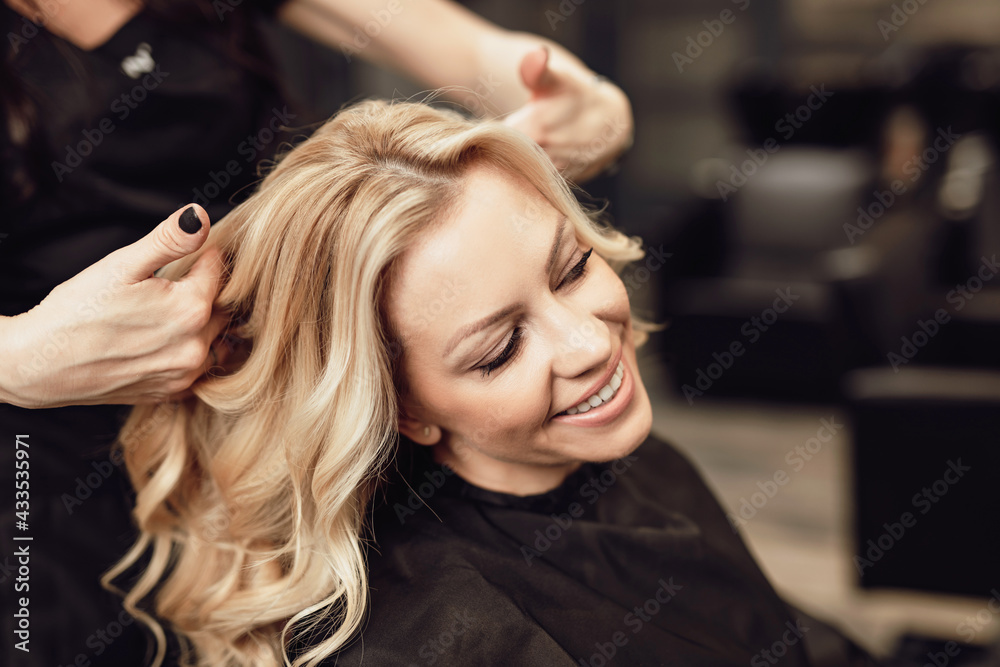 Fototapeta premium Beautiful hairstyle of blond middle-aged woman in modern hair salon...