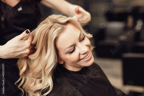 Beautiful hairstyle of blond middle-aged woman in modern hair salon...