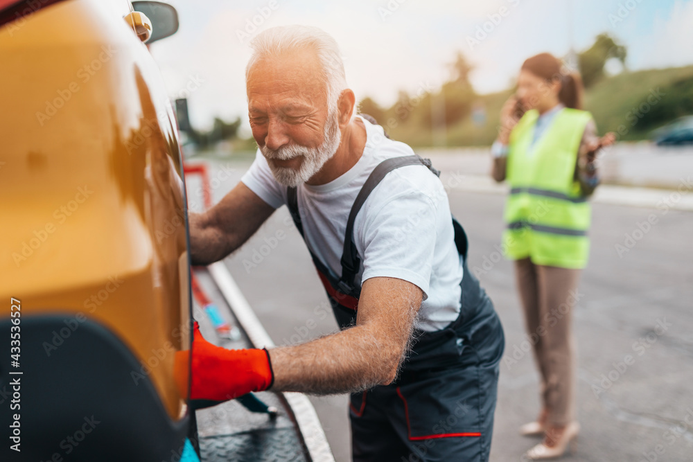 Handsome senior man working in towing service on the road. Roadside assistance concept... Handsome senior man working in towing service on the road. Roadside assistance concept...