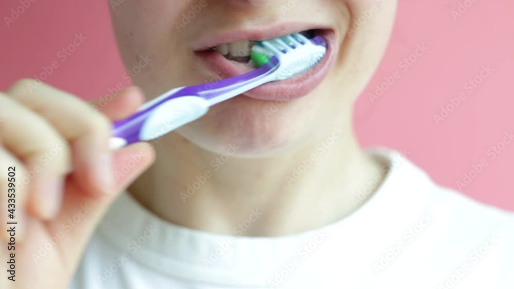 Girl brushes teeth with toothbrush with toothpaste on pink background close-up. Girl brushes teeth with toothbrush with toothpaste on pink background close-up.