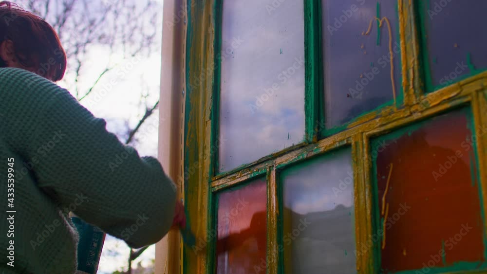 Close up of unrecognizable person paints window with yellow paint on street. Concept of renovation and revivification territory Close up of unrecognizable person paints window with yellow paint on street. Concept of renovation and revivification territory