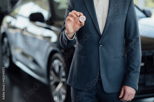 Close up male holding digital money Bitcoin to buy new car. Car exchange with Bitcoin. Cryptocurency © VAKSMANV