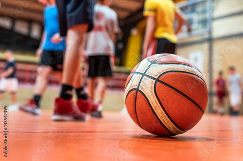 Basketball ball on the floor in sport gym on the court selective focus with blurred feet of unknown children on training sport and development concept © Miljan Živković