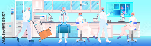 doctors team in masks and protective suits working together in medical laboratory vaccine development