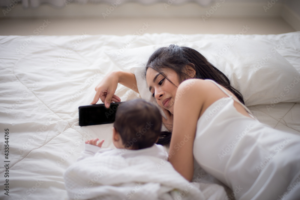 Portrait of beautiful young asian mother looking her newborn baby sleep in bed. Healthcare and medical love lifestyle mother's day concept Portrait of beautiful young asian mother looking her newborn baby sleep in bed. Healthcare and medical love lifestyle mother's day concept