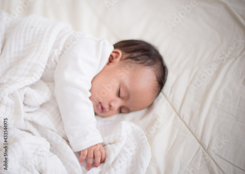 Infants are looking forward in an upside-down position on a white bed, the evolution of Baby girl in the age up to 6 months./Selected focus