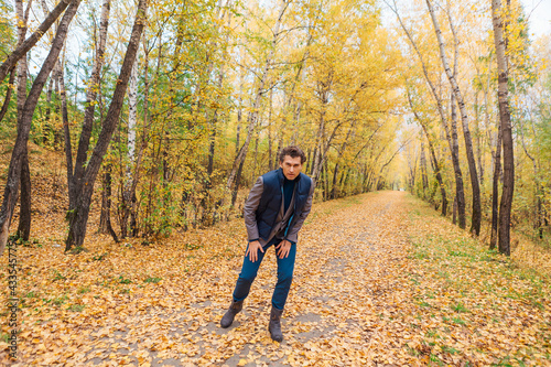 Tall handsome man walking in the autumn alley