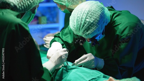 Asian coworker Medical Team Performing Surgical Operation in Operating Room hospital background. Medical stuff bending over patient before operation and putting anesthesia mask on him.