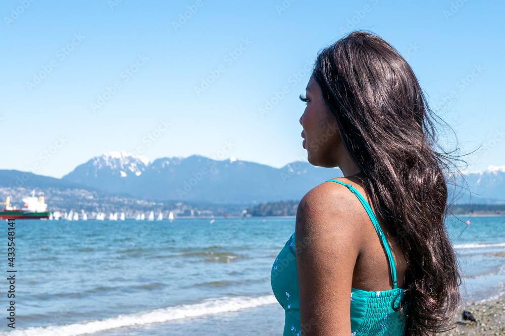 カナダのバンクーバーのビーチにいる黒人系カナダ人の少女と青空と海