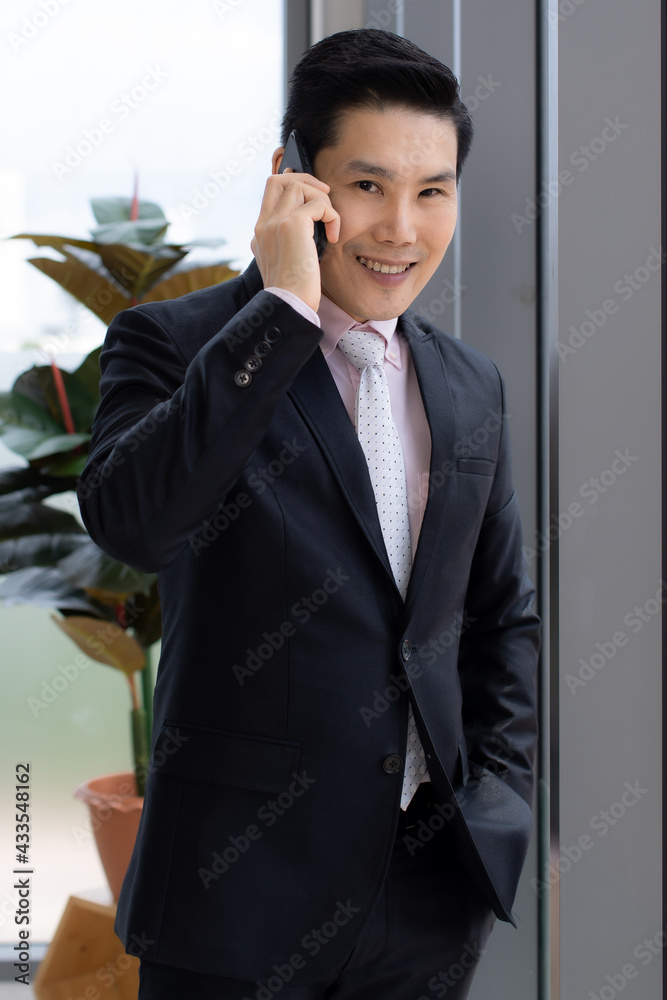 Asian businessman talking on smartphone in office Asian businessman talking on smartphone in office
