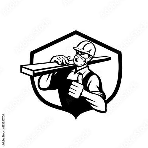 Illustration of a carpenter builder wearing a face mask or disposable N95 particulate respirator carrying lumber on shoulder thumbs up set in shield crest on isolated background done in retro style. 